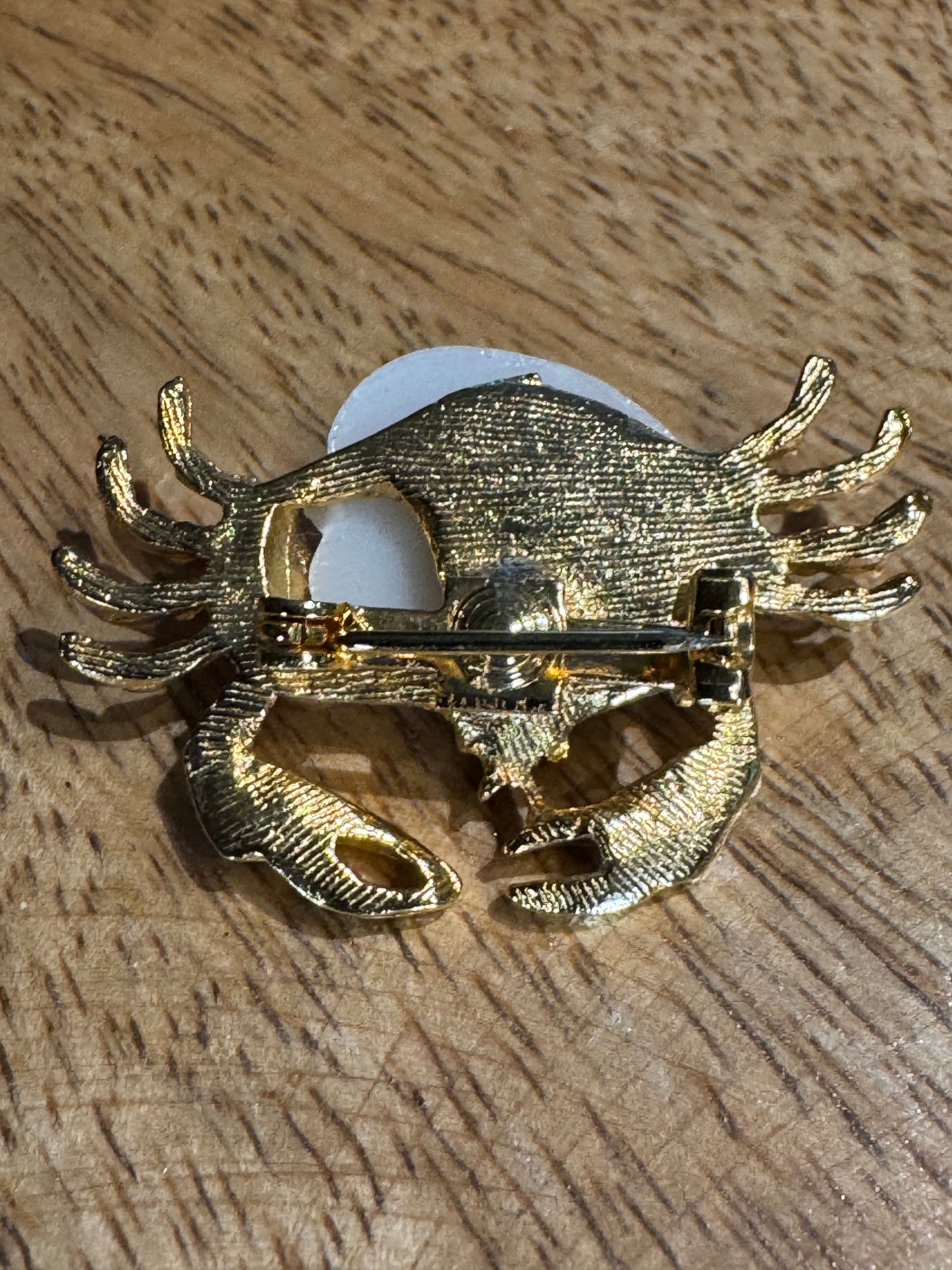 Vintage gold-tone crab brooch featuring a white pearlescent shell body and rhinestone accents