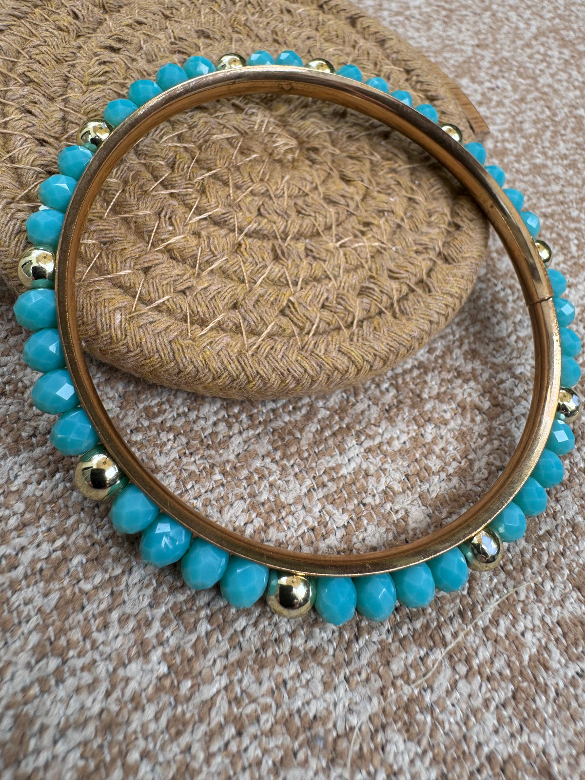 Gold-tone bangle bracelet featuring faceted turquoise-colored beads