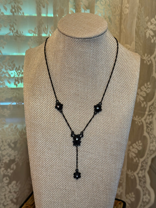 Antiqued black metal necklace featuring floral-shaped stations accented with small clear rhinestones