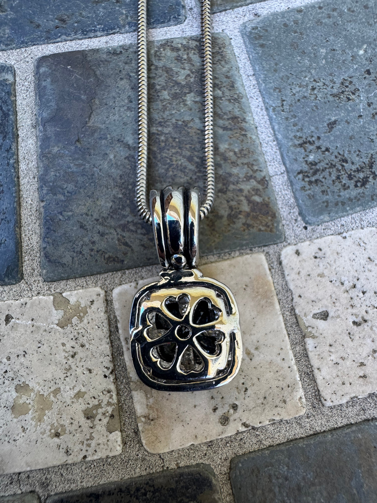 Pendant Necklace Featuring a Black Gemstone Set in a Textured Silver and Gold-accented Frame