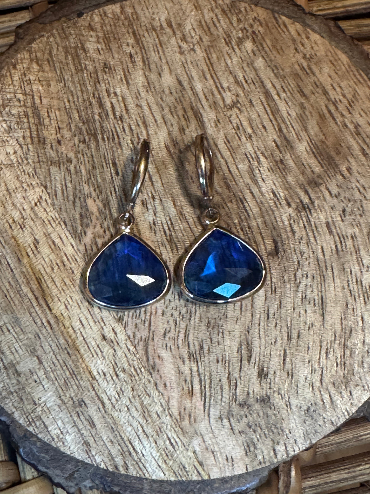Vintage-inspired silver tone earrings with bezel set blue faceted stone