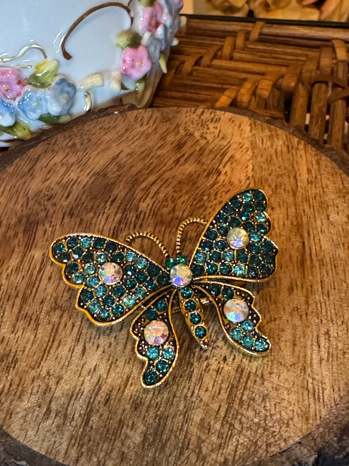 Gold-tone butterfly brooch features sparkling teal and iridescent rhinestone crystals