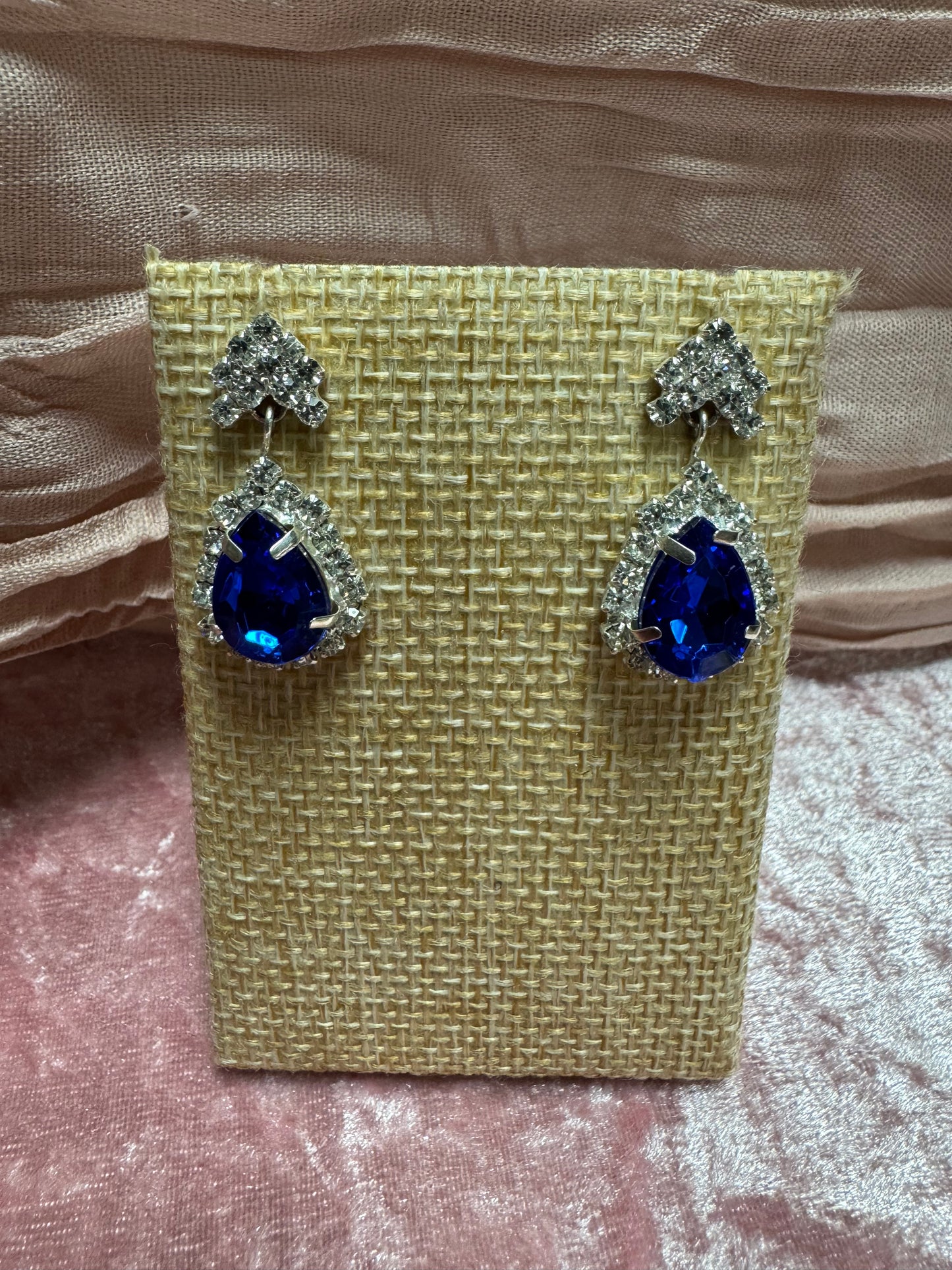 Silver-tone dangle earrings featuring a large blue teardrop crystal haloed by smaller white rhinestones