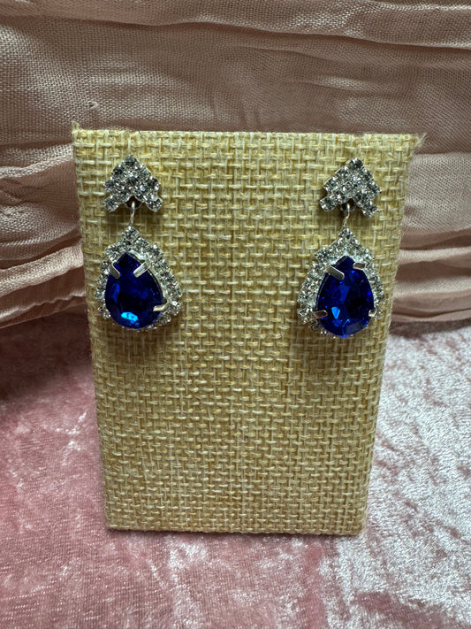 Silver-tone dangle earrings featuring a large blue teardrop crystal haloed by smaller white rhinestones