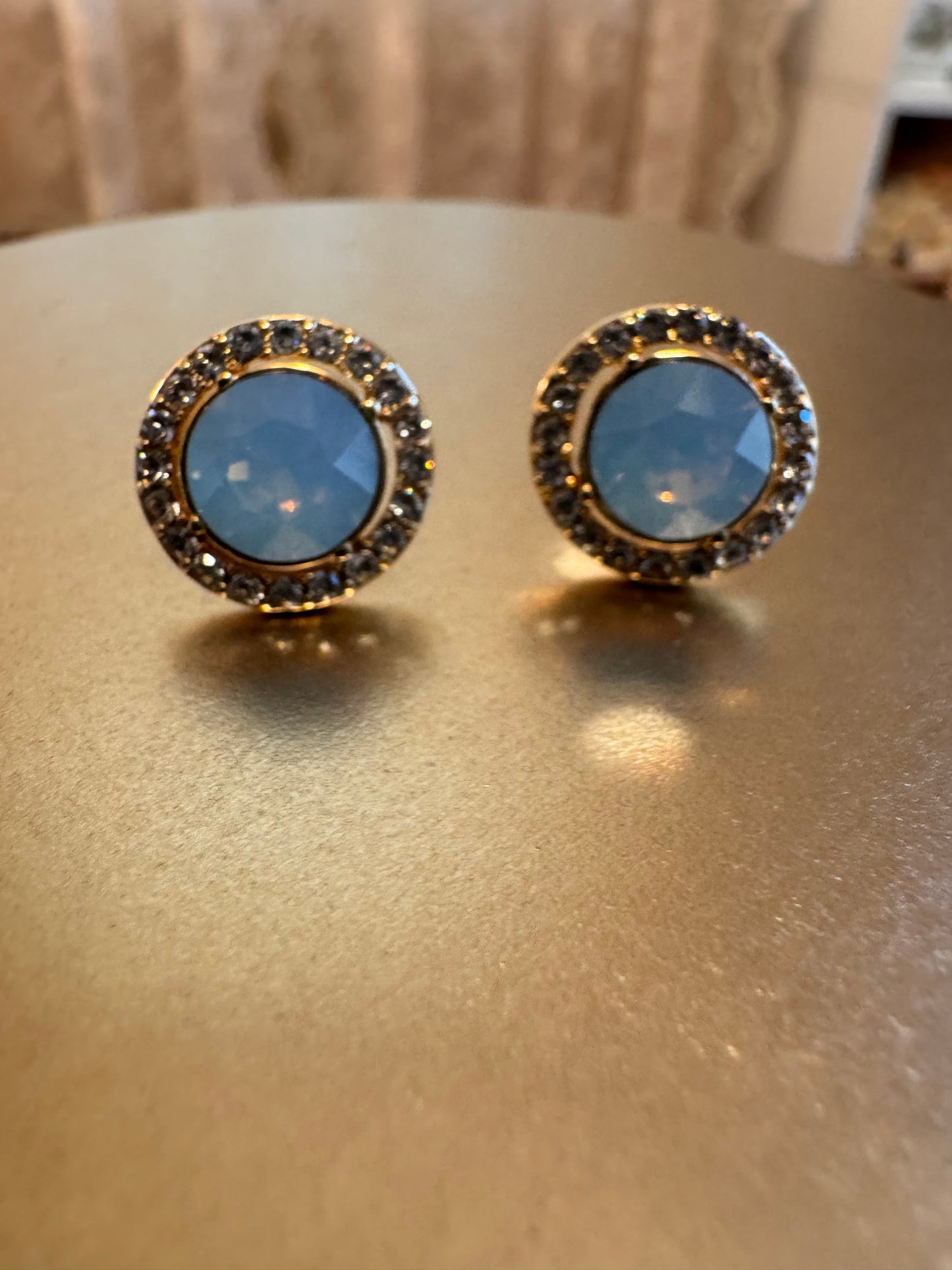 Elegant vintage-inspired halo stud earrings feature a mesmerizing light blue opal center stone,