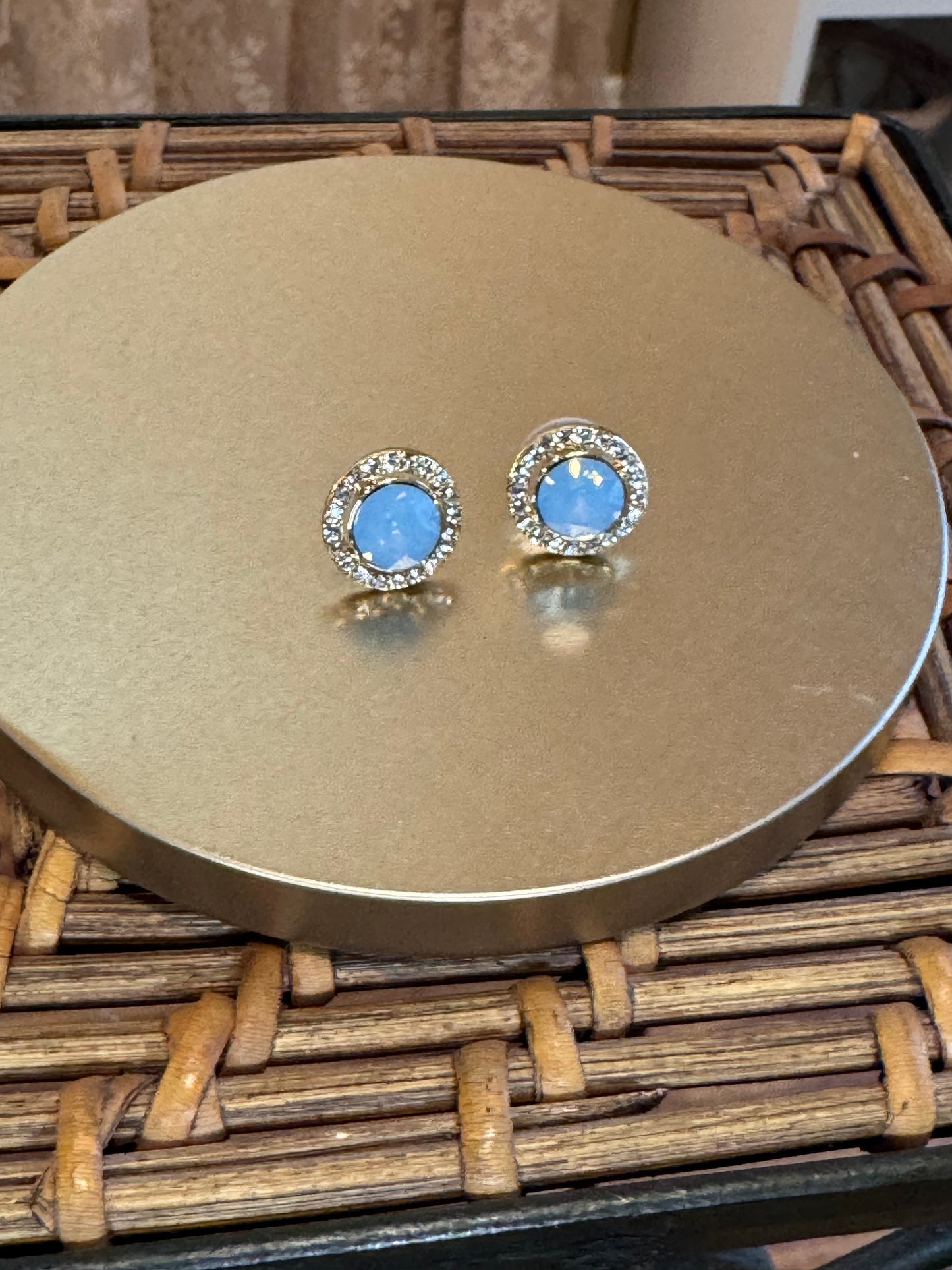Elegant vintage-inspired halo stud earrings feature a mesmerizing light blue opal center stone,