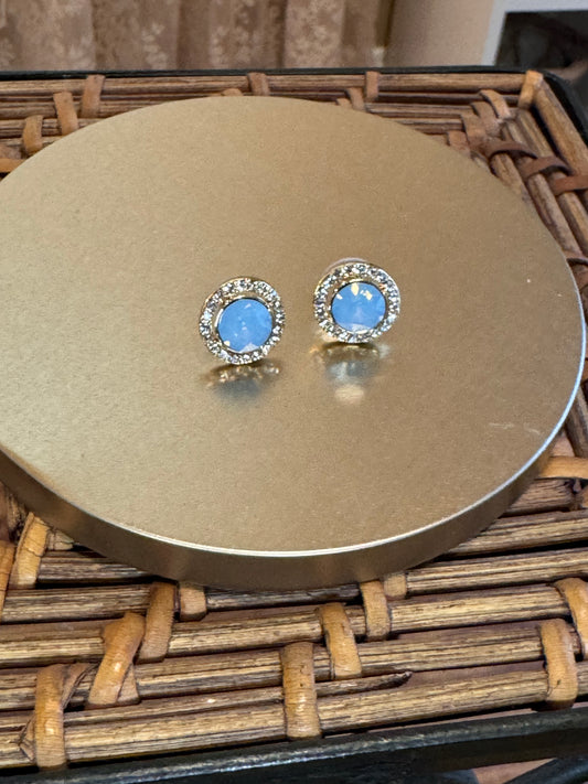 Elegant vintage-inspired halo stud earrings feature a mesmerizing light blue opal center stone,