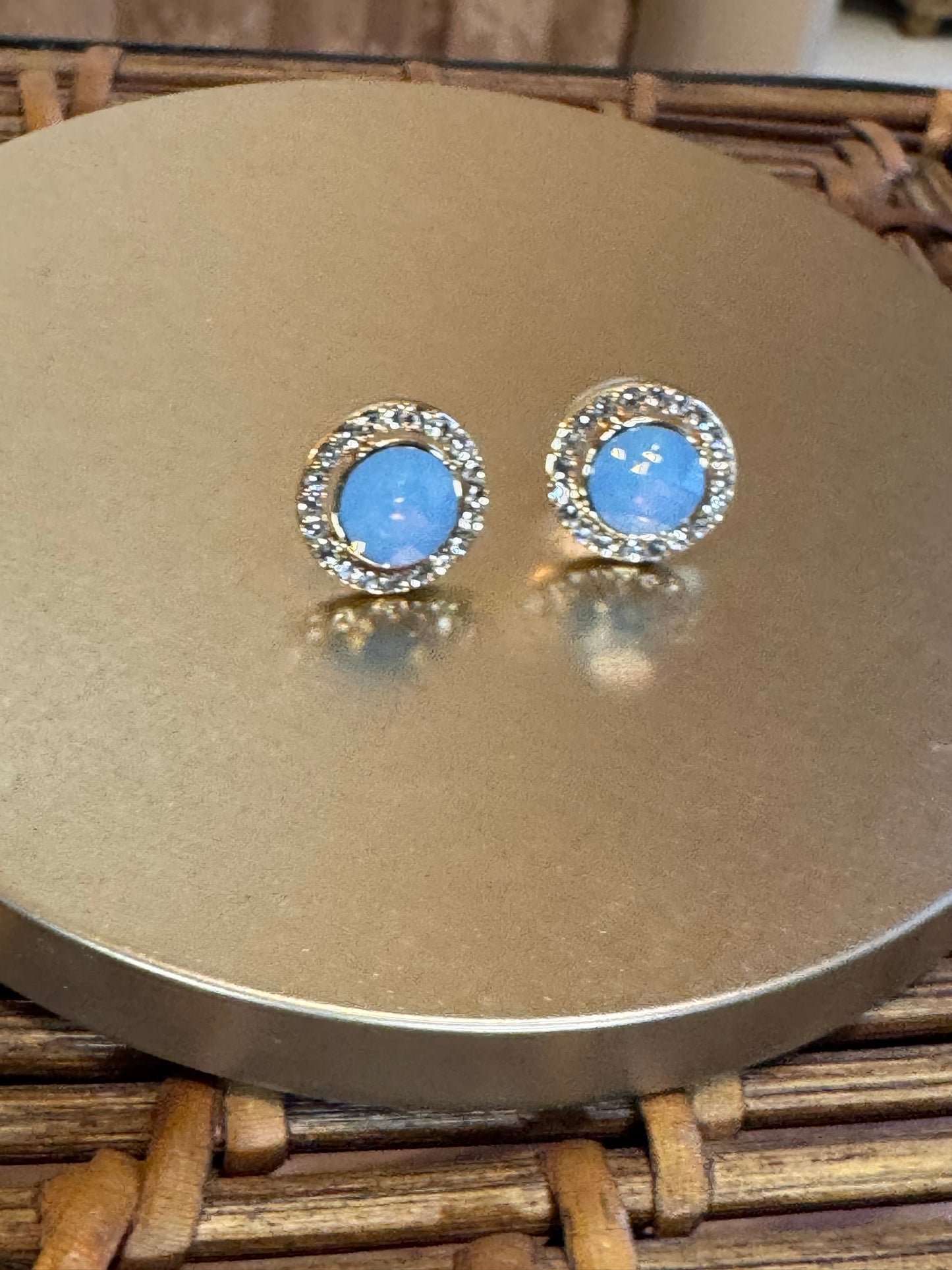 Elegant vintage-inspired halo stud earrings feature a mesmerizing light blue opal center stone,
