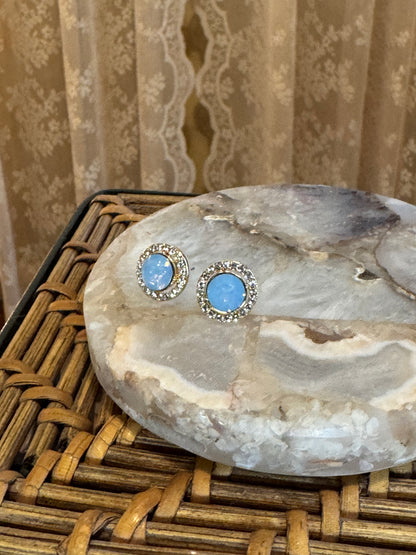 Elegant vintage-inspired halo stud earrings feature a mesmerizing light blue opal center stone,