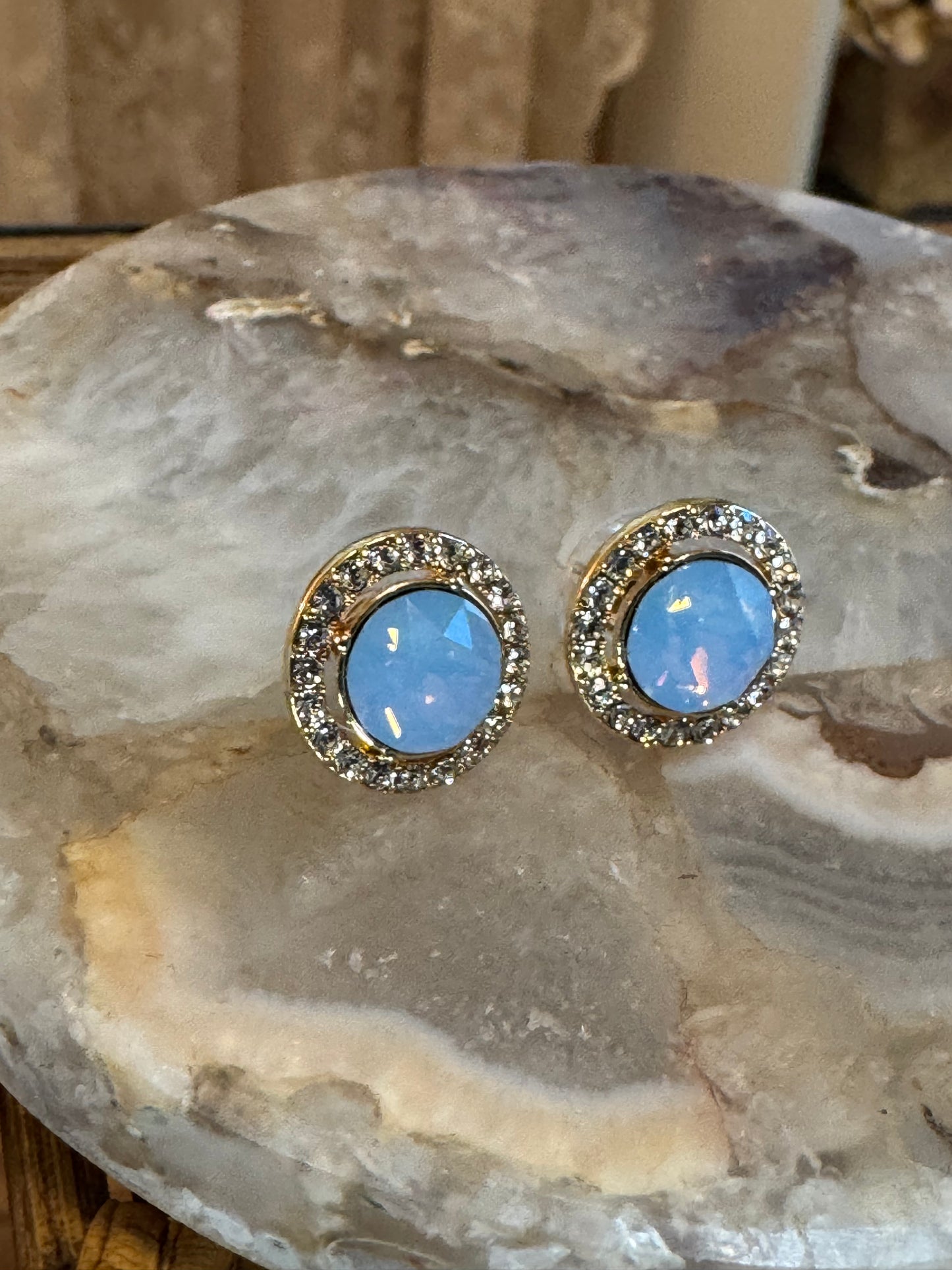 Elegant vintage-inspired halo stud earrings feature a mesmerizing light blue opal center stone,