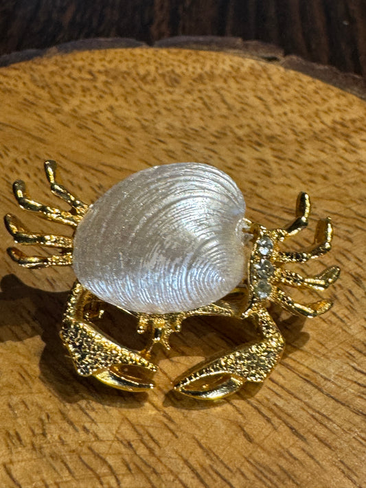 Vintage gold-tone crab brooch featuring a white pearlescent shell body and rhinestone accents