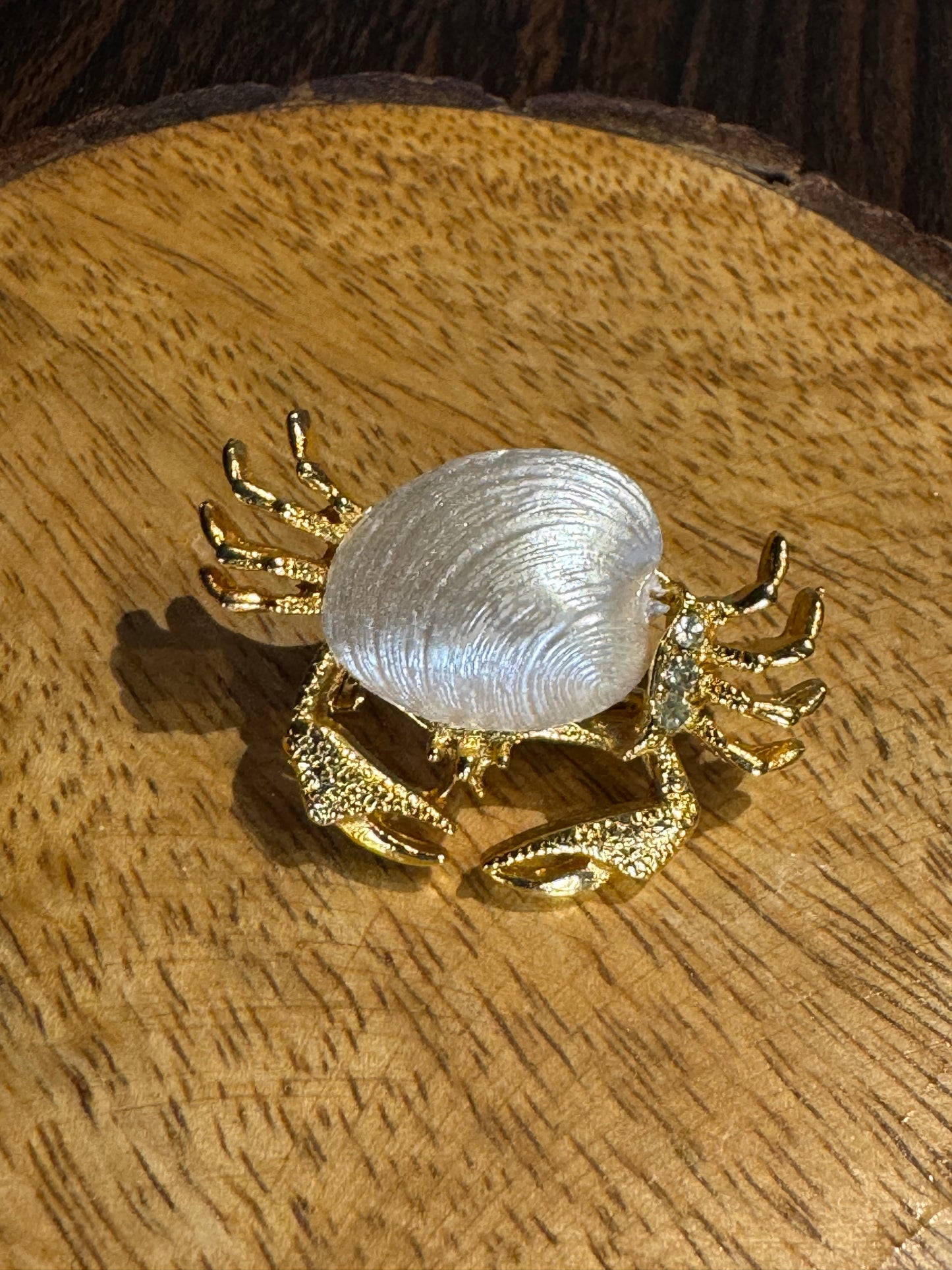 Vintage gold-tone crab brooch featuring a white pearlescent shell body and rhinestone accents