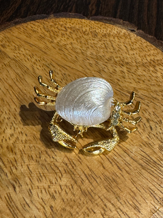 Vintage gold-tone crab brooch featuring a white pearlescent shell body and rhinestone accents