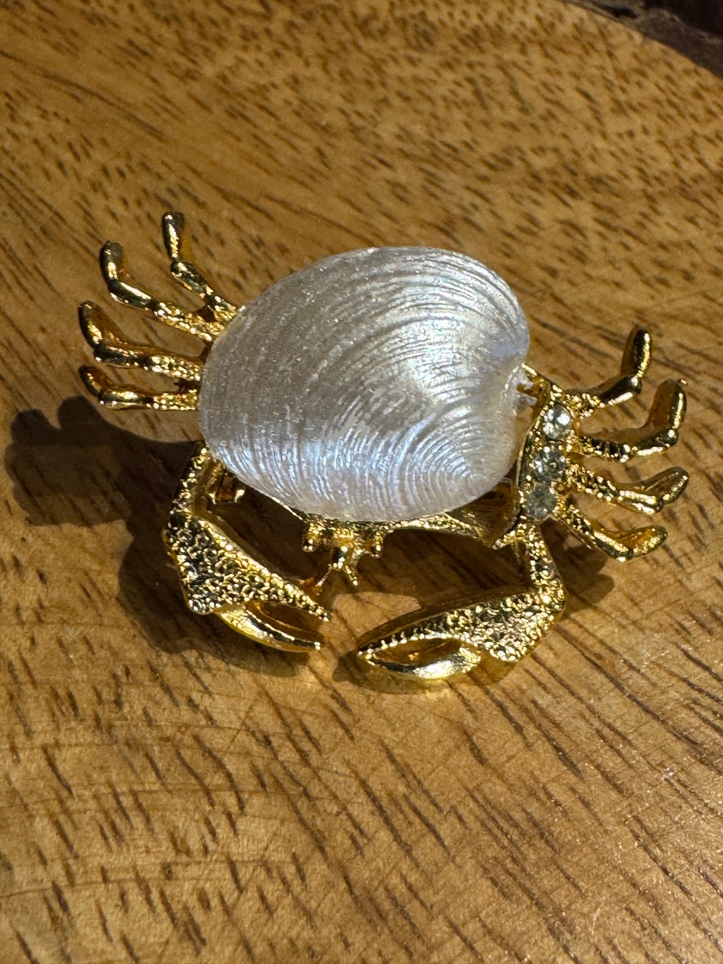 Vintage gold-tone crab brooch featuring a white pearlescent shell body and rhinestone accents
