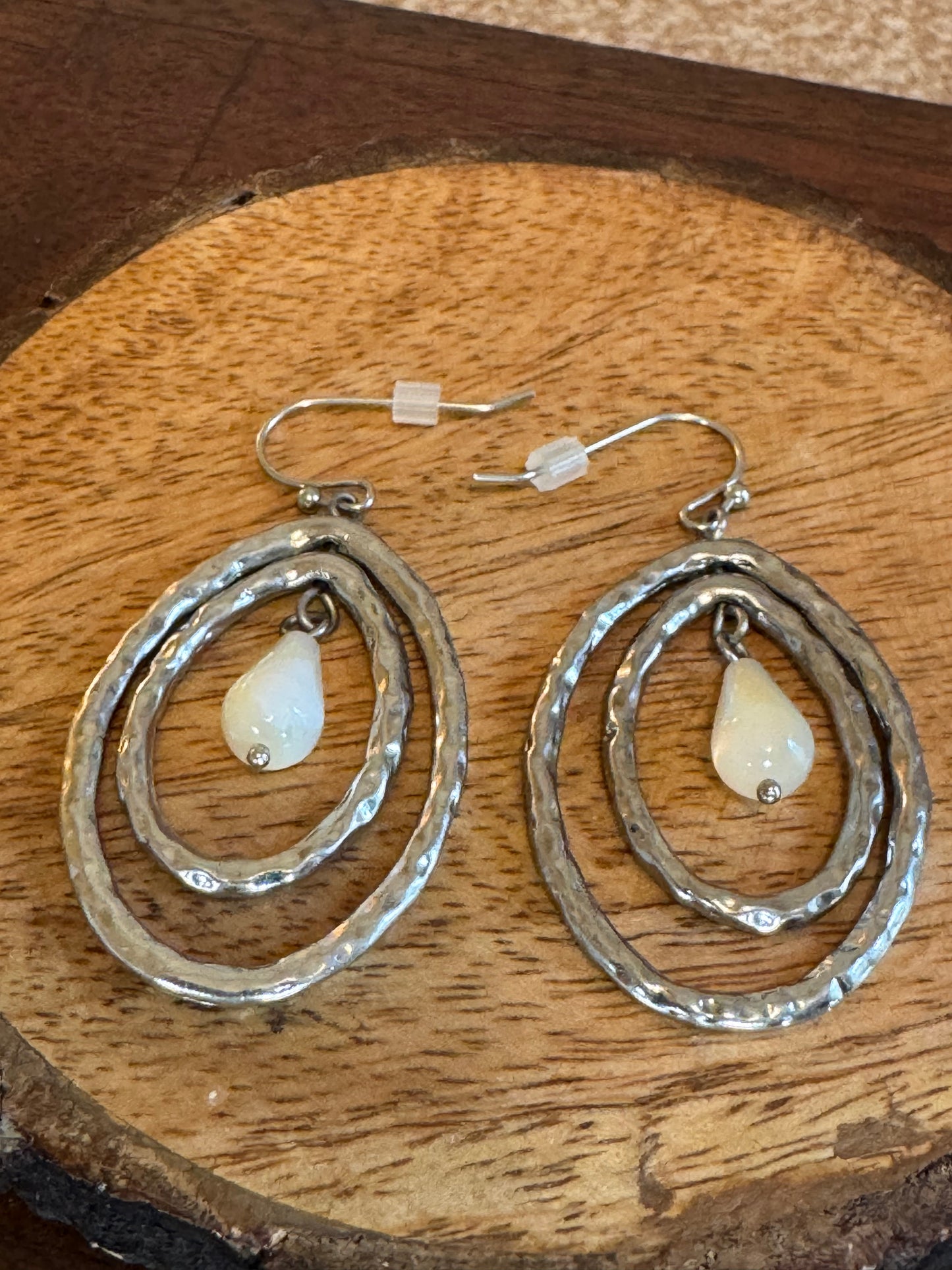 Lia Sophia earrings feature a silver-tone hammered oval design with a mother of pearl pearlescent drop